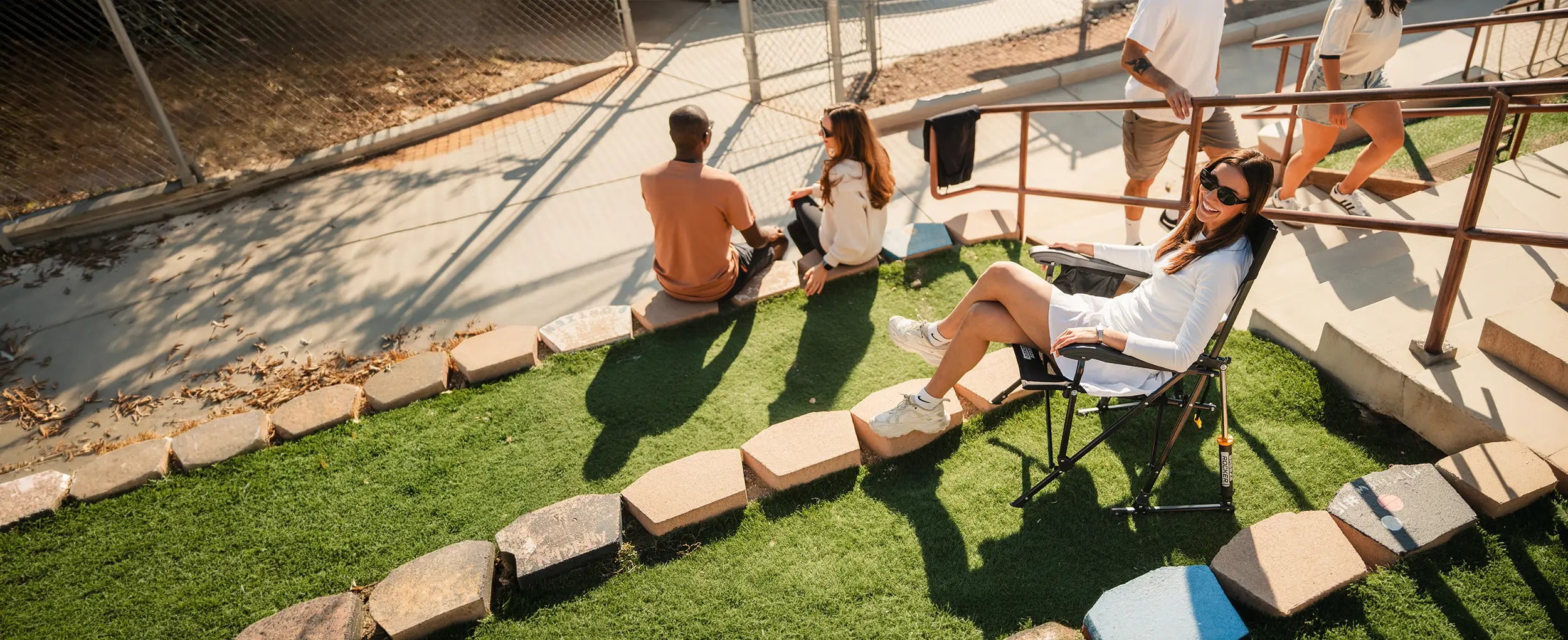 A woman sitting at a park in her black BreezeRocker chair.